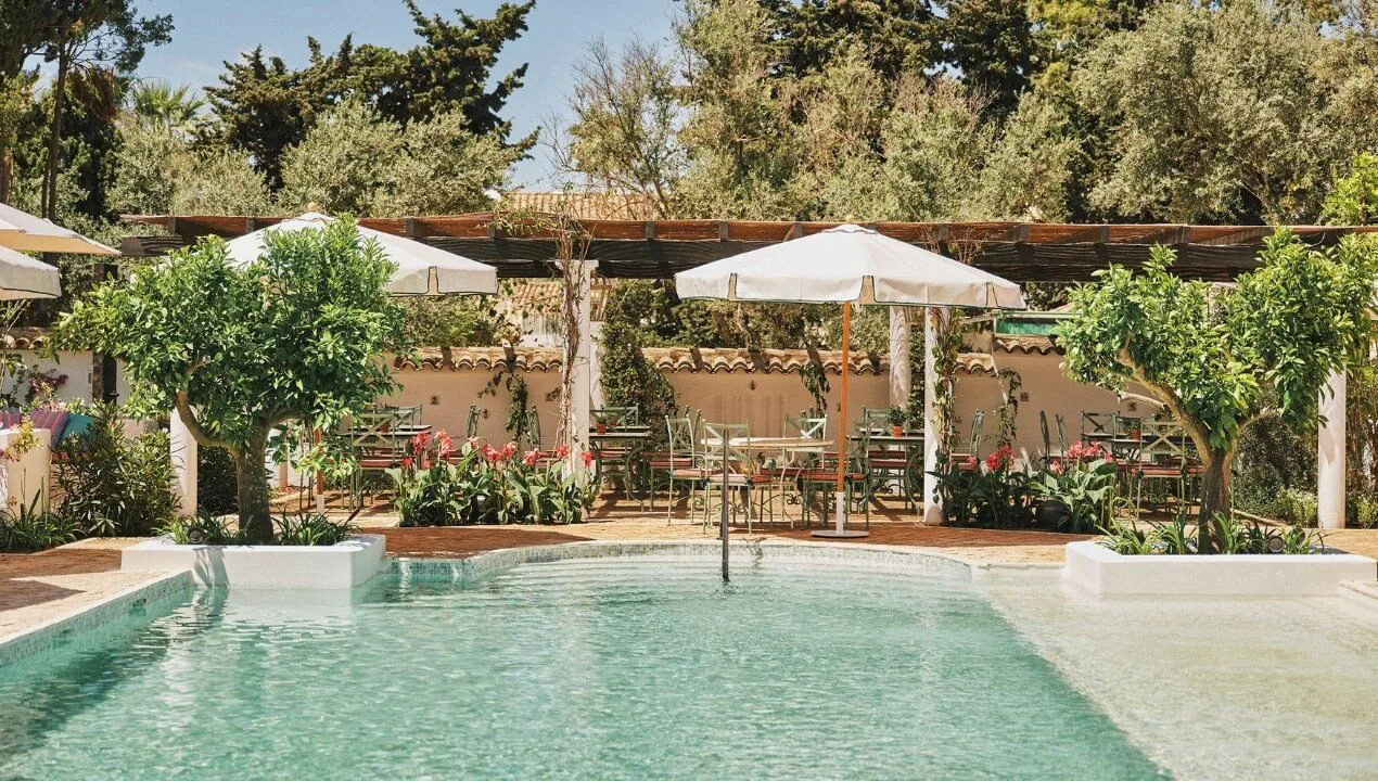 Pool with fountain and shaded tables among olive trees at Finca Ana María, Marbella Club