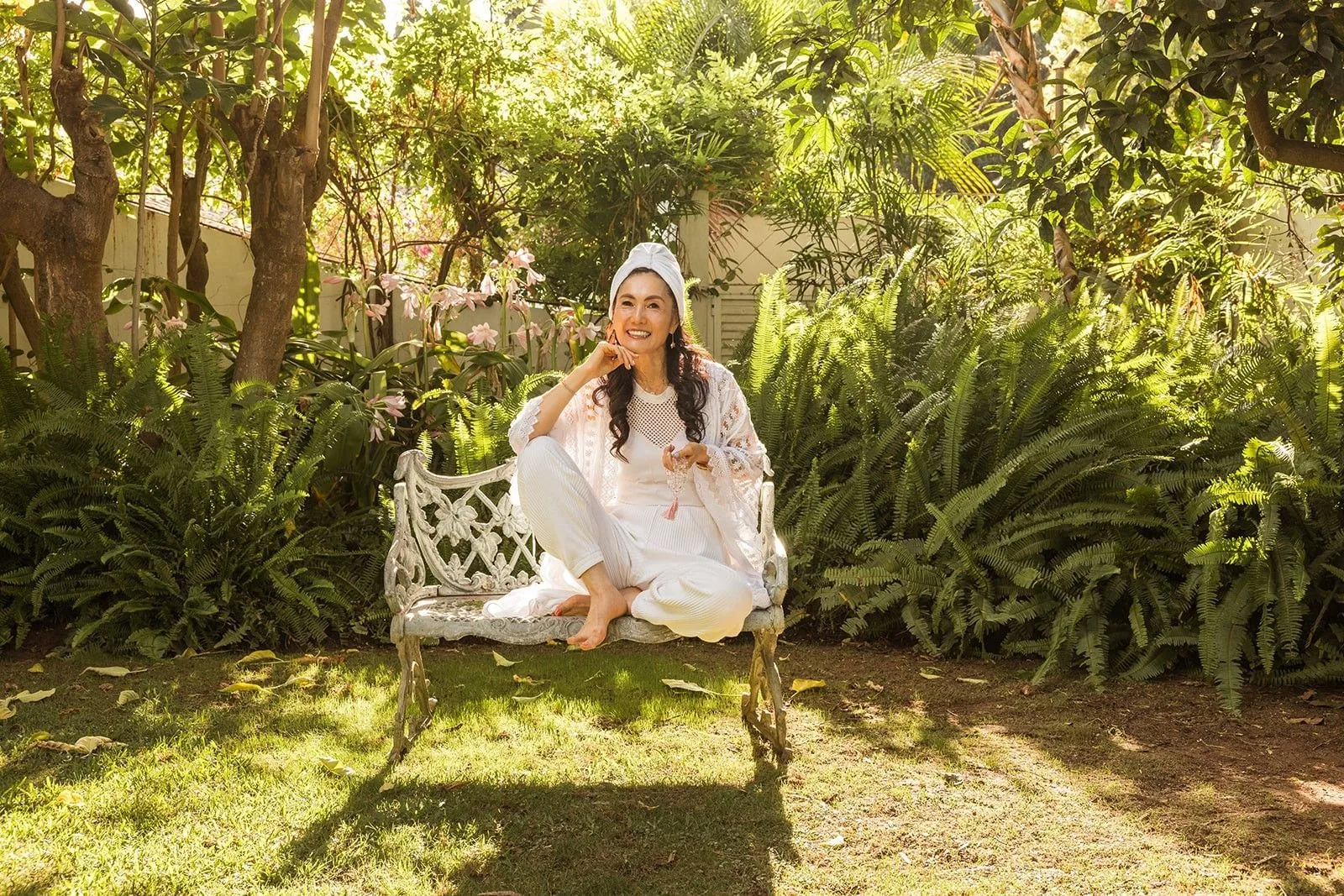Woman in white seated on a garden bench among tropical plants at the Marbella Club